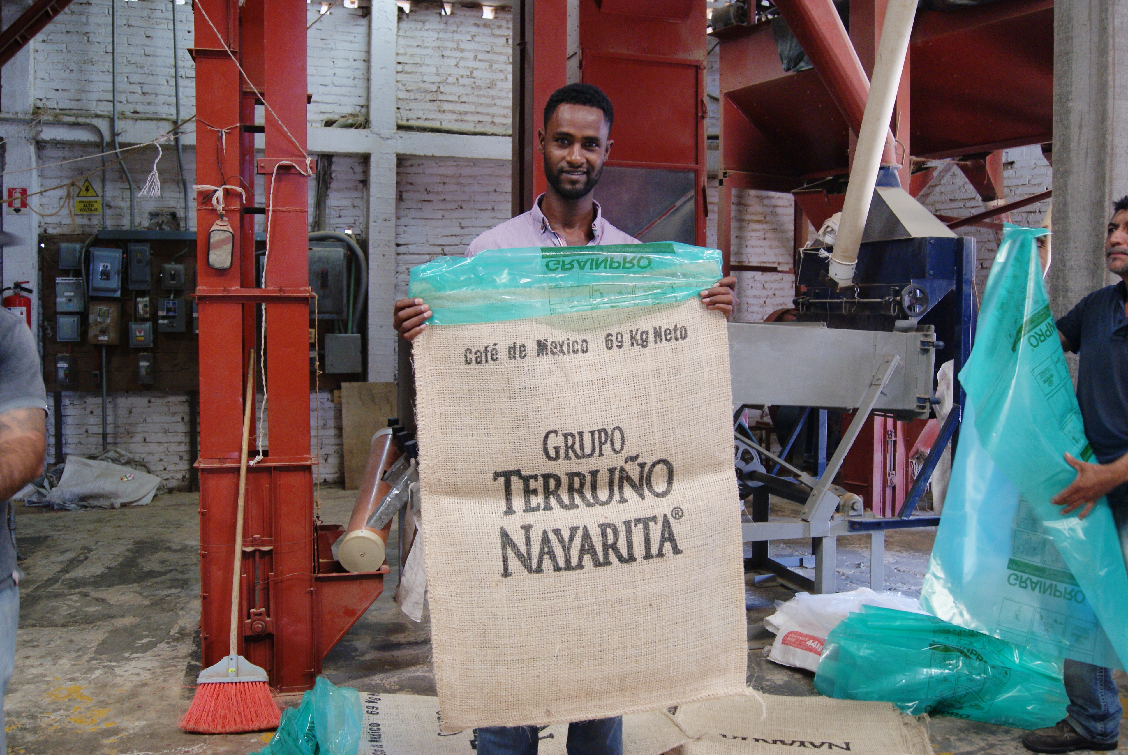 Mengistu holds up a sisal bag with a GrainPro liner while working in the El Duende Dry Mill in 2019.
