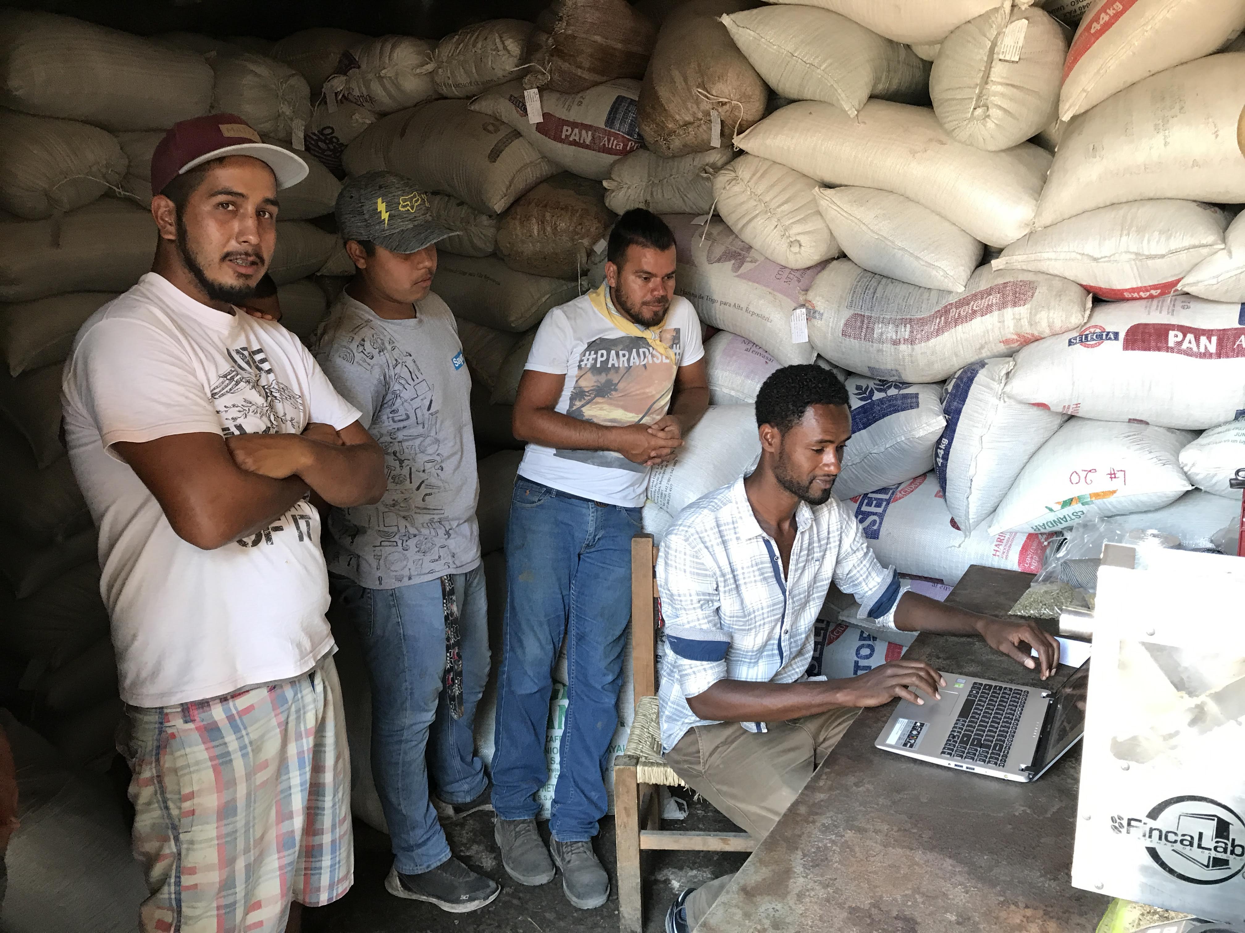 Photo of Mengistu, while a harvest intern in Mexico, sharing photos of Ethiopian coffee production with children of producers and workers at the Rustico Wet Mill in El Cuarenteño, Nayarit.